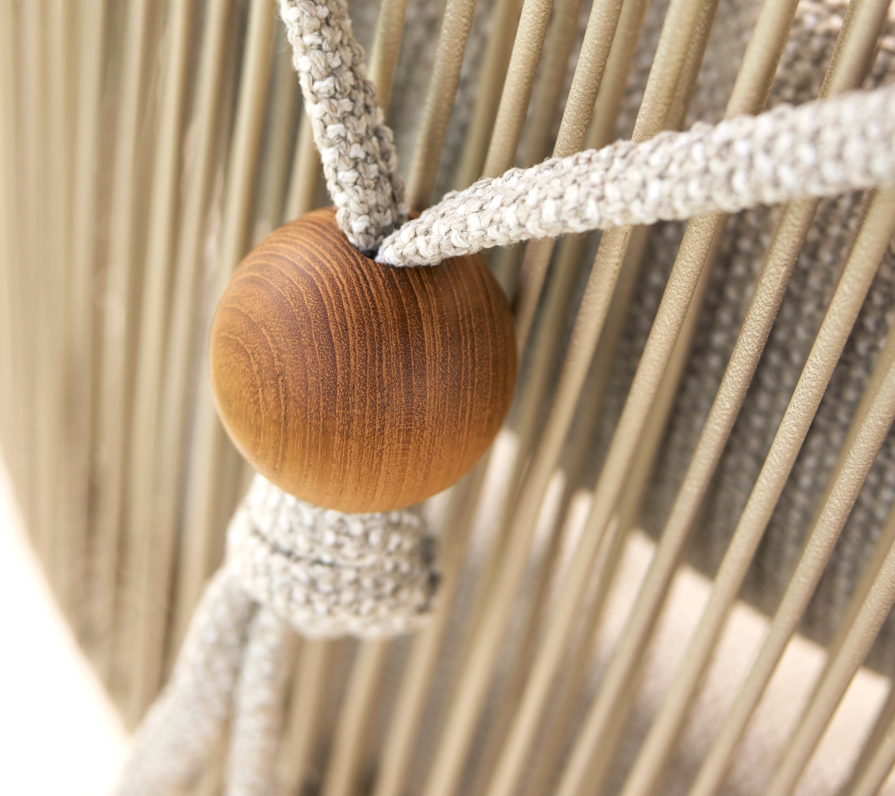 Gros plan d'un support de coussin de cou pour une chaise Hive, comportant une perle en bois et des sangles en tissu tissées.