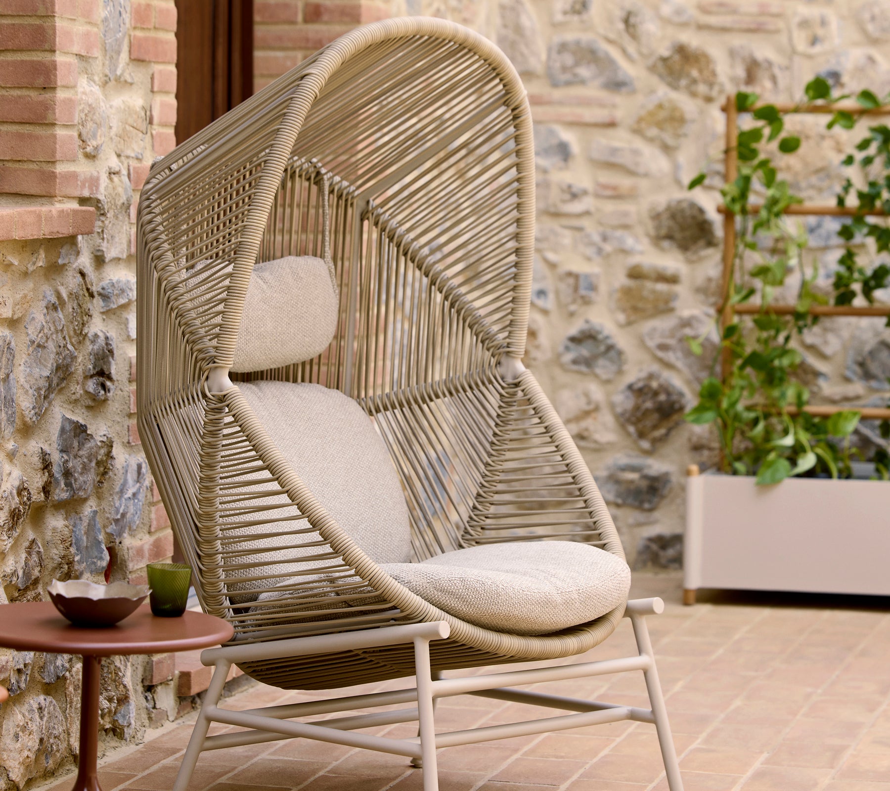 La chaise Hive en couleur sable présente un design tissé unique avec un siège rembourré et une arche distinctive en hauteur pour le confort et le style.