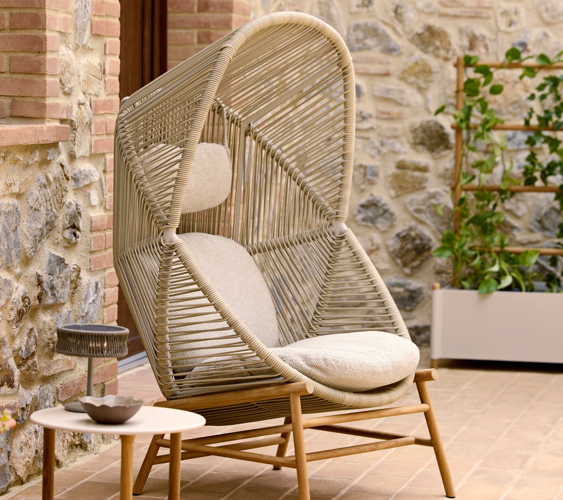 Chaise Hive élégante en couleur sable avec un design à torsion unique, complétée par des coussins moelleux pour plus de confort.