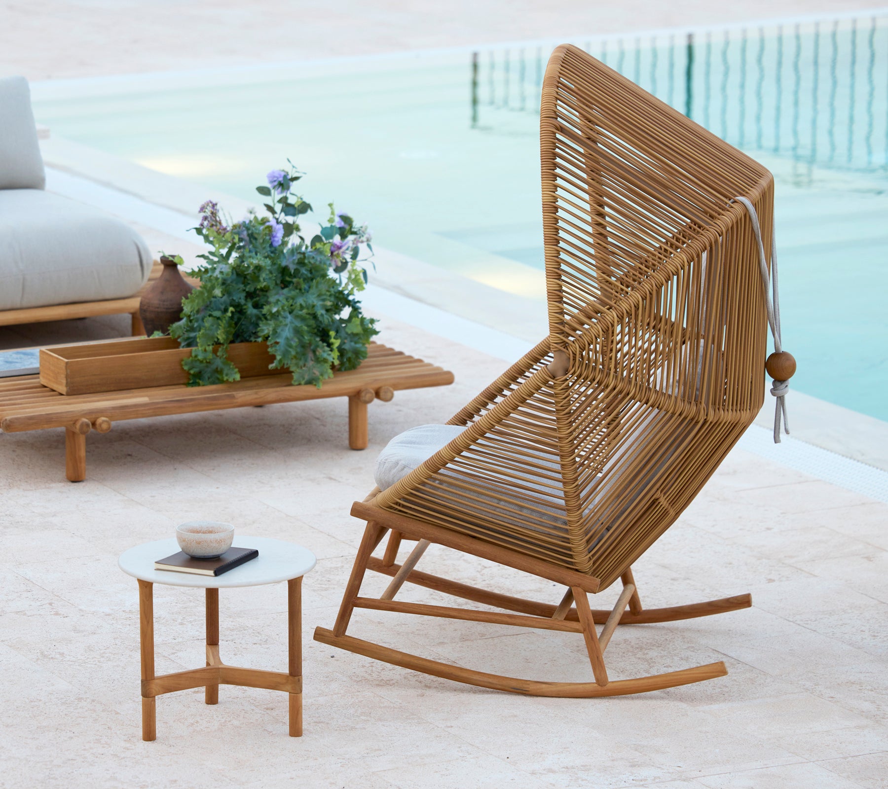 Un fauteuil à bascule Hive élégant à côté d'une table basse Twist et d'une table basse Sticks, complété par une plante en pot.