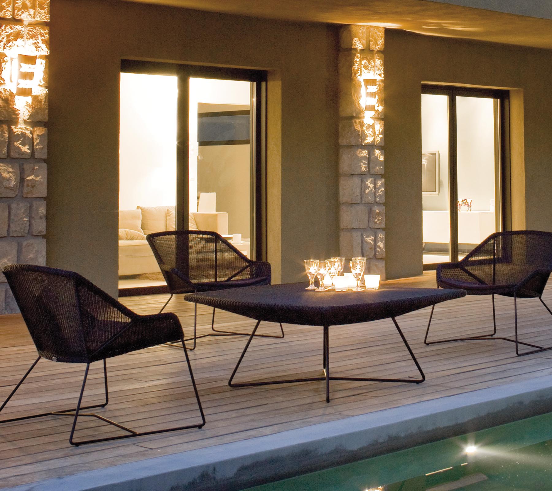 Un agencement de sièges de salon élégant avec quatre chaises en maille noires autour d'une table épurée, éclairé par un éclairage ambiant doux.