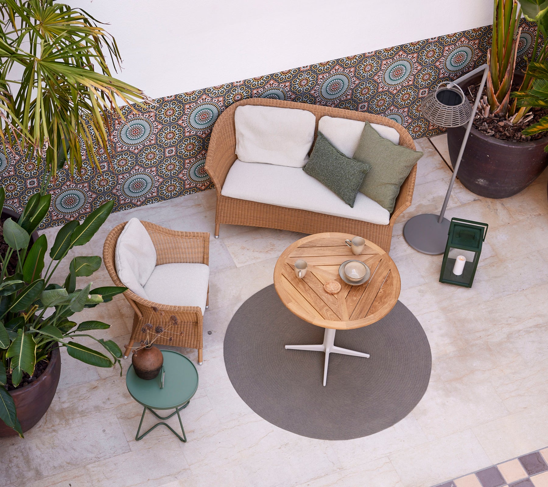 Un cadre cosy avec un canapé et une chaise Lansing, une table ronde et de la verdure, créant une atmosphère détendue. Parfait pour le loisir.