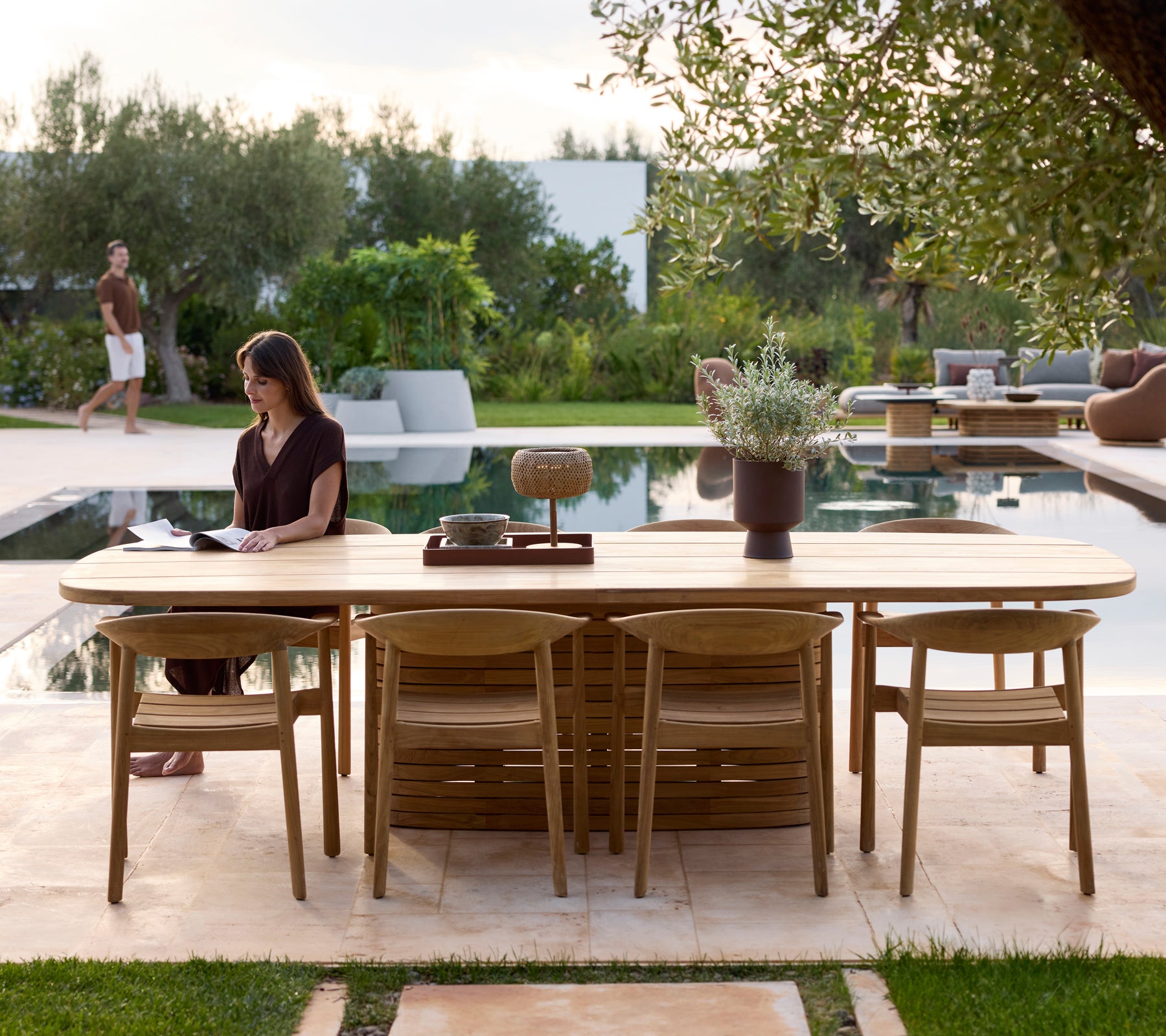 Mobilier de jardin moderne avec des chaises à côté d'une piscine entourée de verdure.