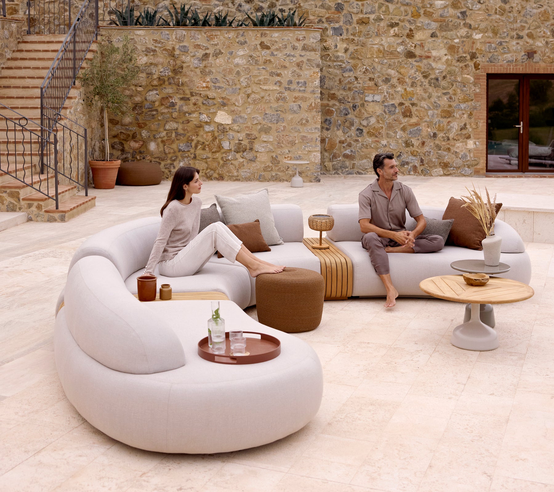 Un aménagement de salon moderne avec un canapé courbé, un pouf rond et une table basse élégante avec un plateau de club, créant une ambiance chaleureuse.