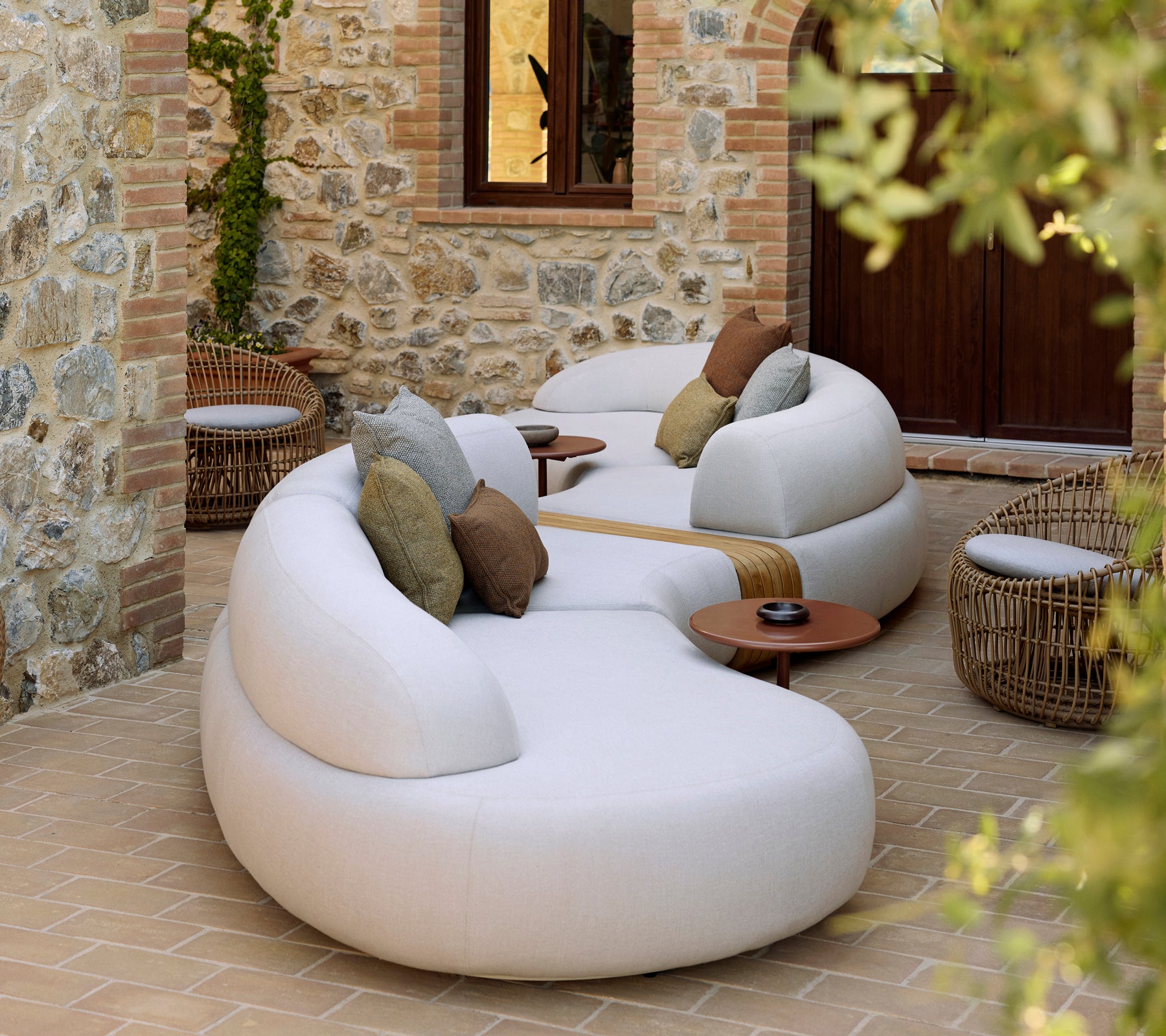 Salon chaleureux avec une chaise ronde Nest et une table basse Glaze, agrémenté de coussins décoratifs dans un cadre paisible.