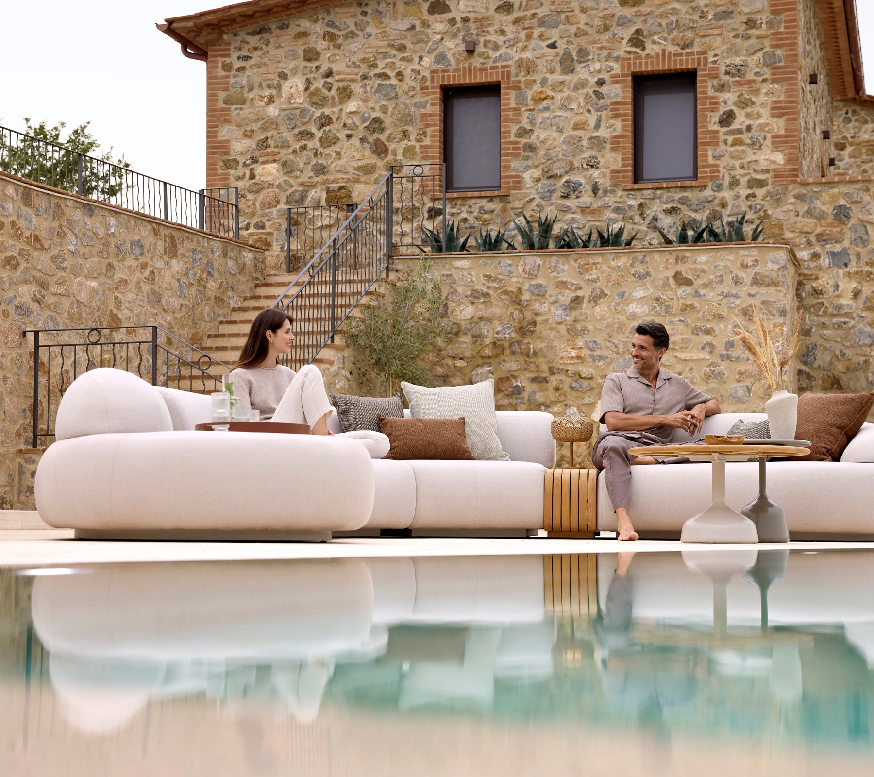 Deux personnes se détendent sur un canapé lounge moelleux, associé à une table basse Glaze et une table basse moelleuse, reflétant une atmosphère sereine.