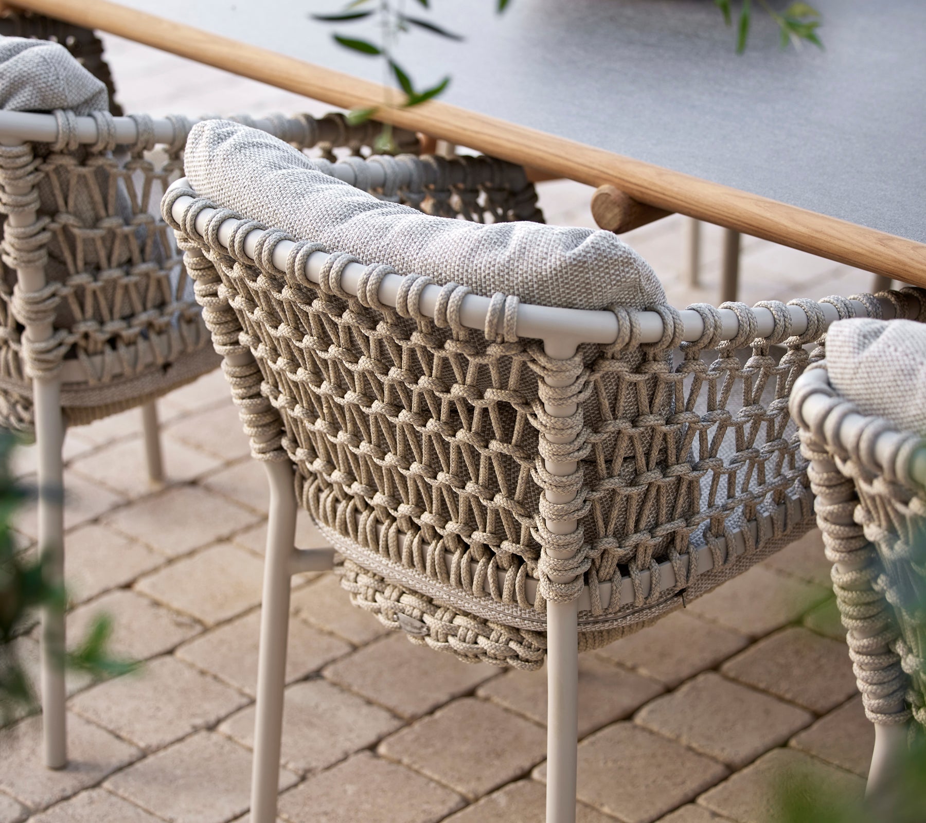 Chaises de salle à manger confortables avec un design tissé et des coussins moelleux, parfaites pour un repas en plein air élégant.
