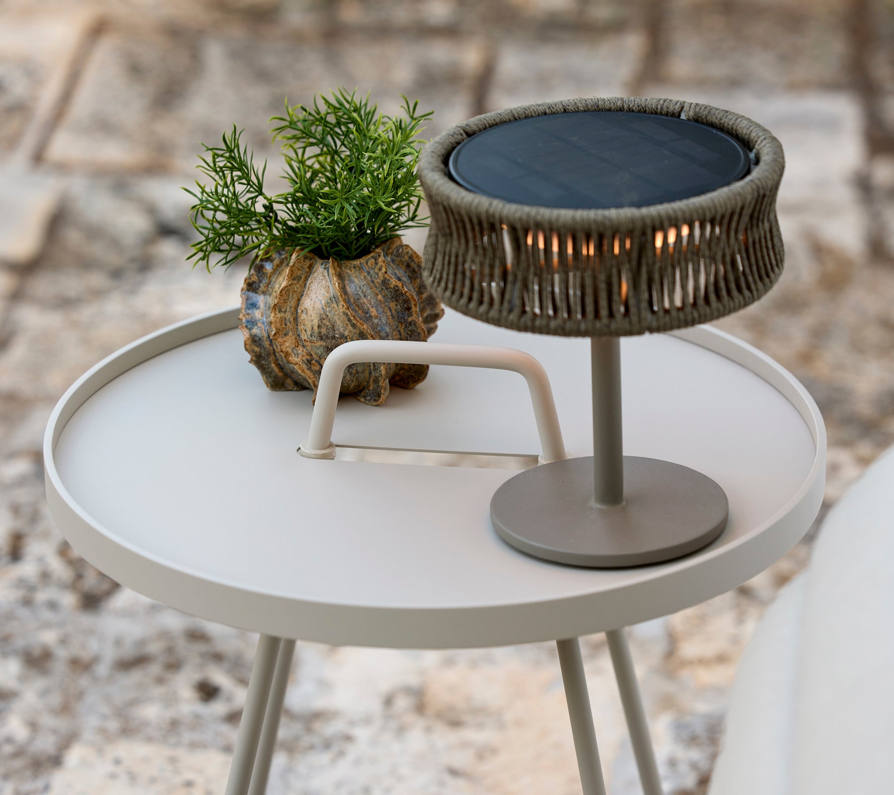 Table d'appoint grise moderne avec une plante verte et une lampe de table élégante.