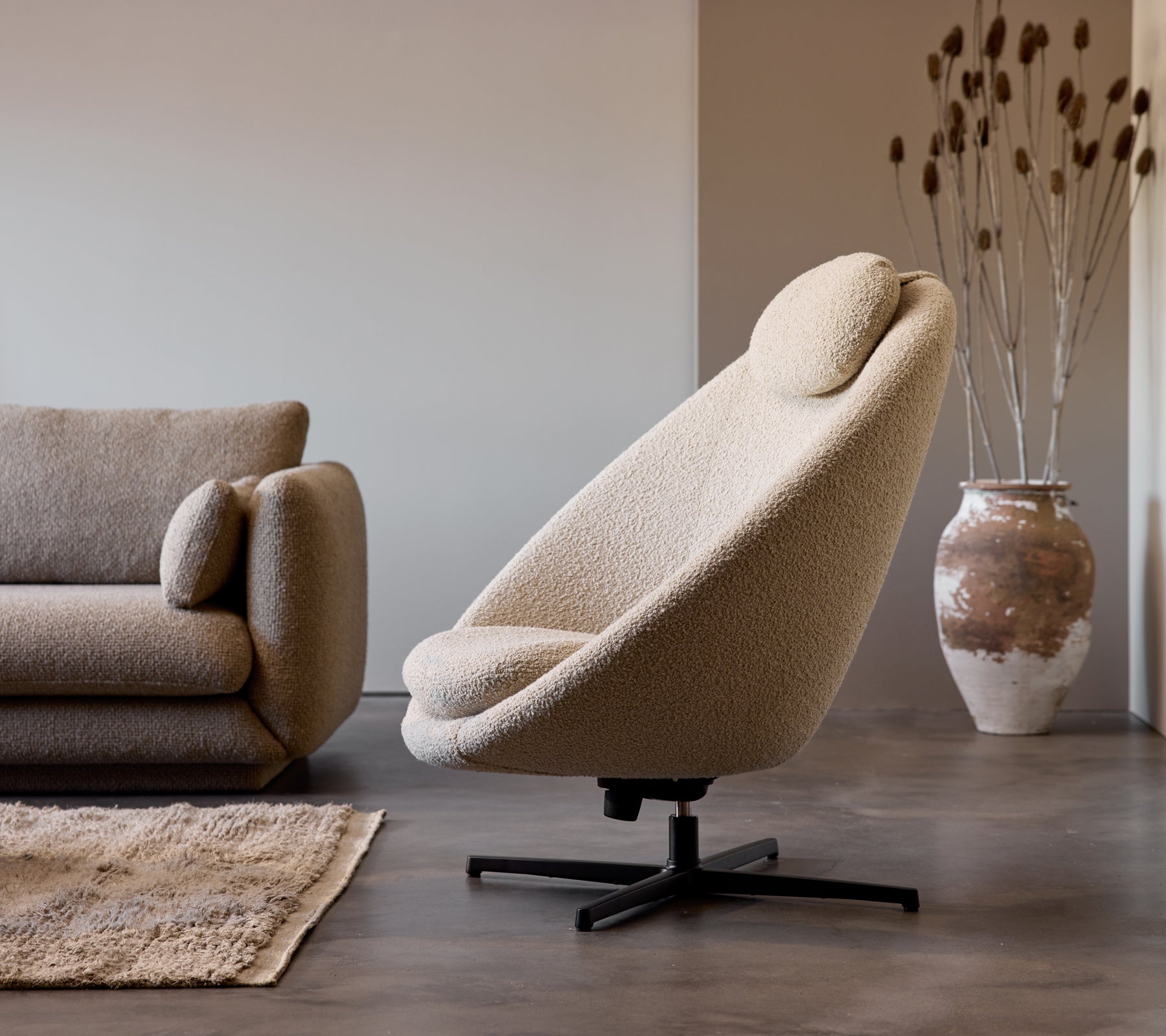 Fauteuil Pace en tissu taupe à côté d'un sofa Bloom 3 places, complété par un vase décoratif et une texture de sol subtile.
