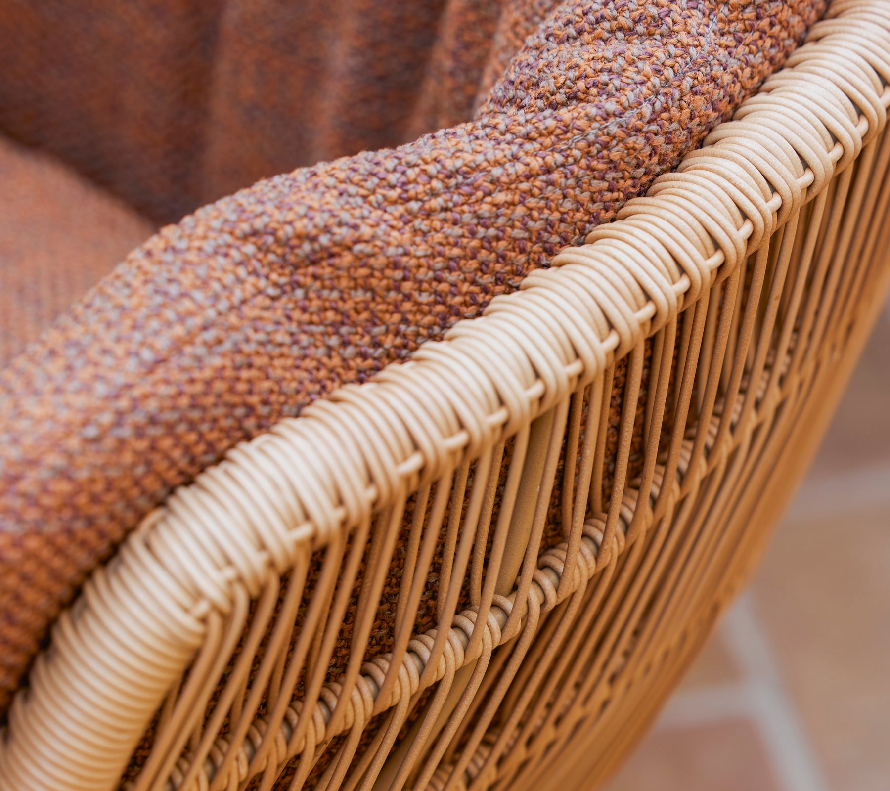 Gros plan sur une chaise de salle à manger Stay avec un coussin Rise texturé de couleur brune et un cadre en fibre naturelle tissée.