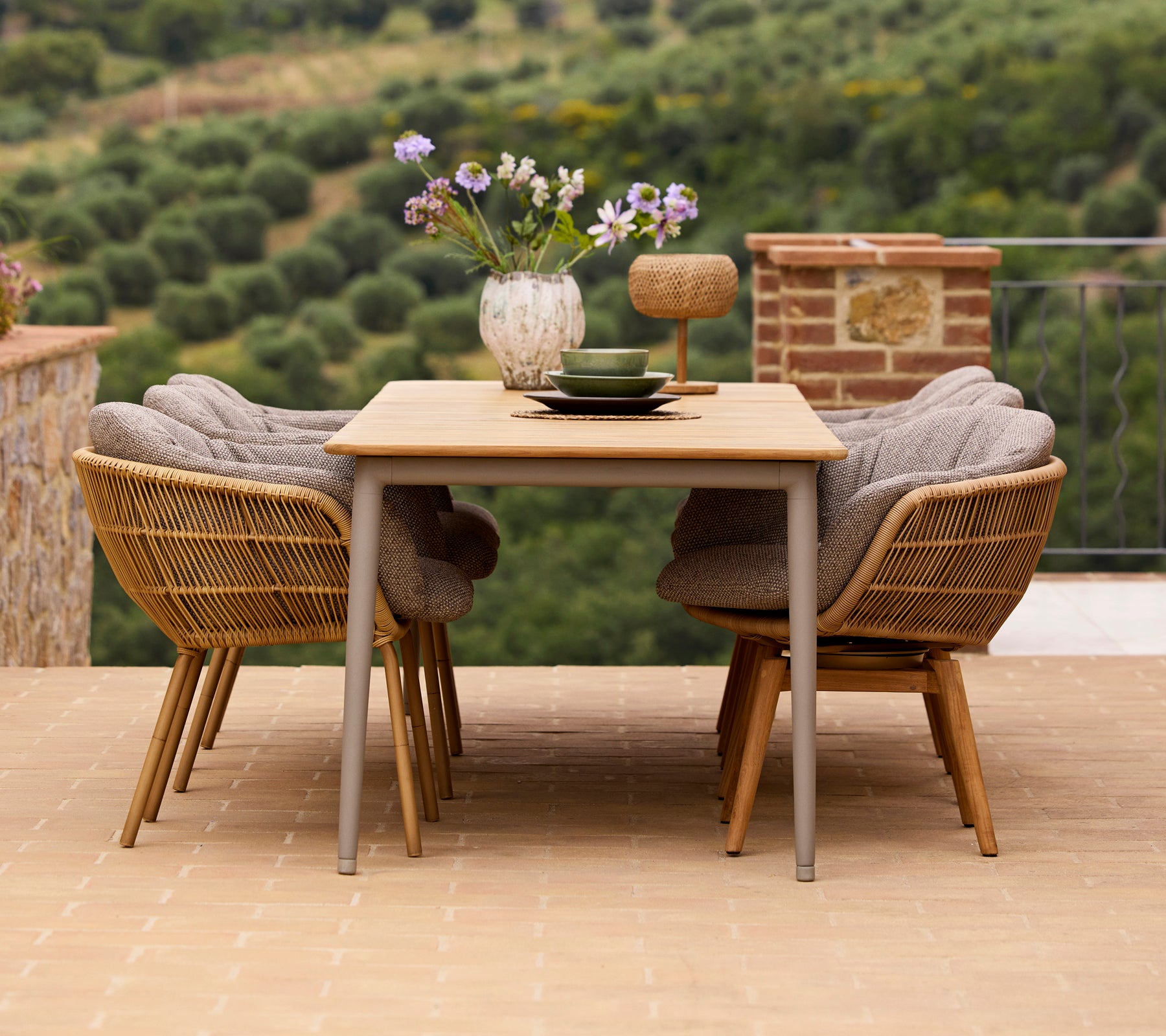 Aménagement de salle à manger élégant comprenant une table en bois, deux chaises Stay avec des pieds en aluminium, et un vase de fleurs avec des accessoires décoratifs.