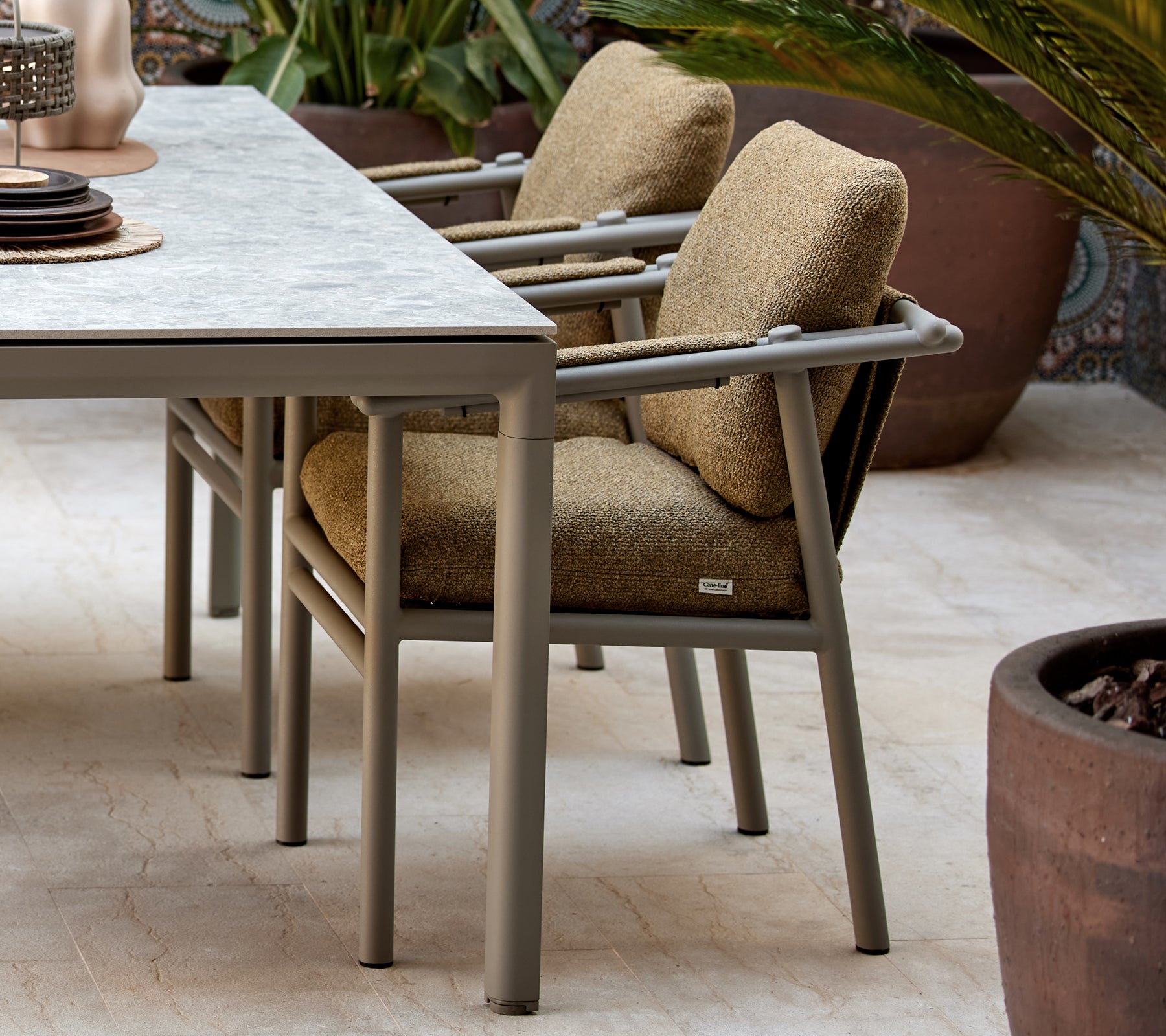 Deux chaises de salle à manger avec des coussins moelleux, présentant un design moderne avec des pieds robustes, placées à côté d'une table avec des objets décoratifs.