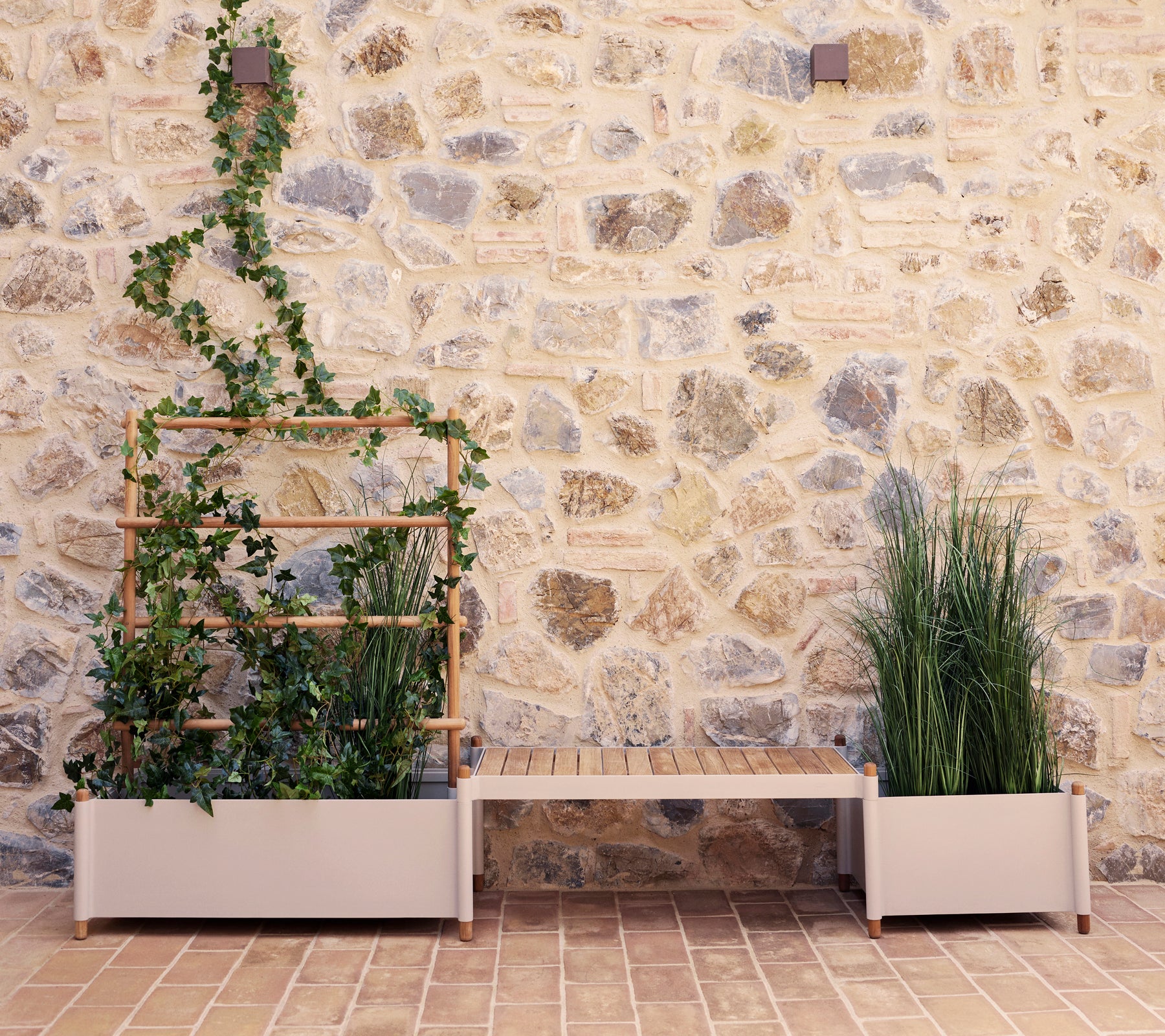 Banc de plantes Sticks avec de la verdure contre un mur en pierre, présentant un support de plantes vertical et deux grands pots.