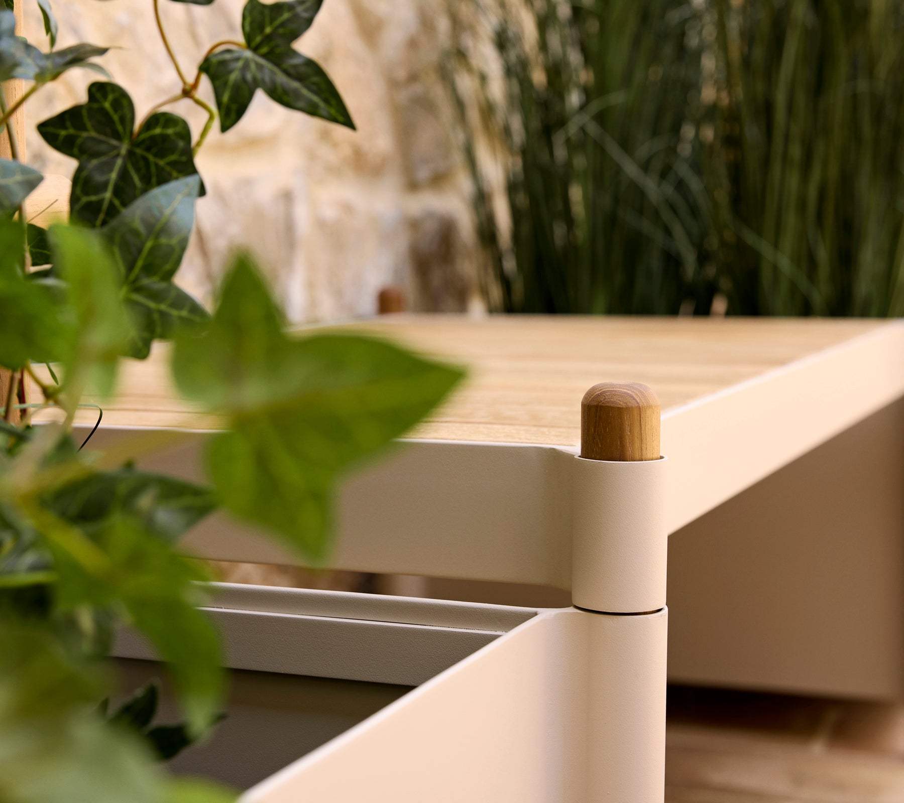 Un banc élégant avec un dessus en bois et des bords doux, accompagné de verdure dans un pot, améliorant une atmosphère sereine.