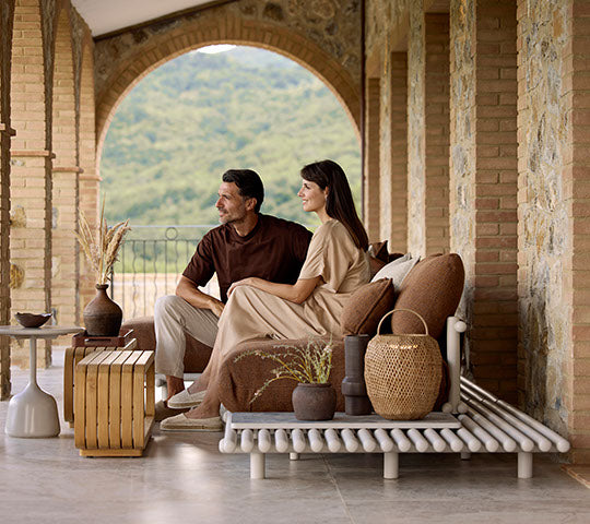 Un couple est assis ensemble sur un canapé élégant, complété par une table basse, des vases décoratifs et une lampe suspendue élégante.