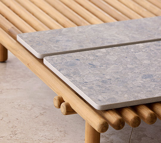 Une plateforme en bois présente deux plateaux en pierre, mettant en avant un design moderne avec des éléments naturels pour une présentation élégante.