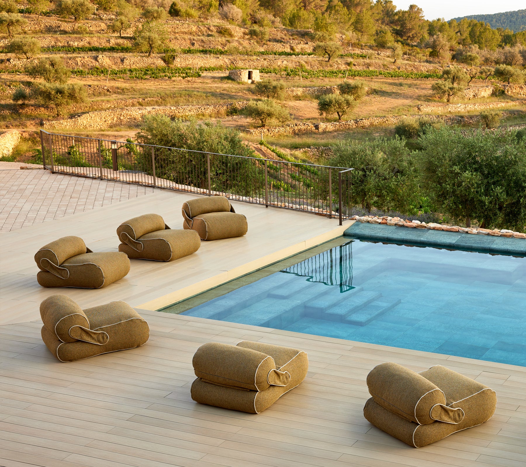 Un cadre serein avec des sièges de salon rembourrés disposés près d'une piscine tranquille, entourée d'une végétation luxuriante et d'un paysage pittoresque.