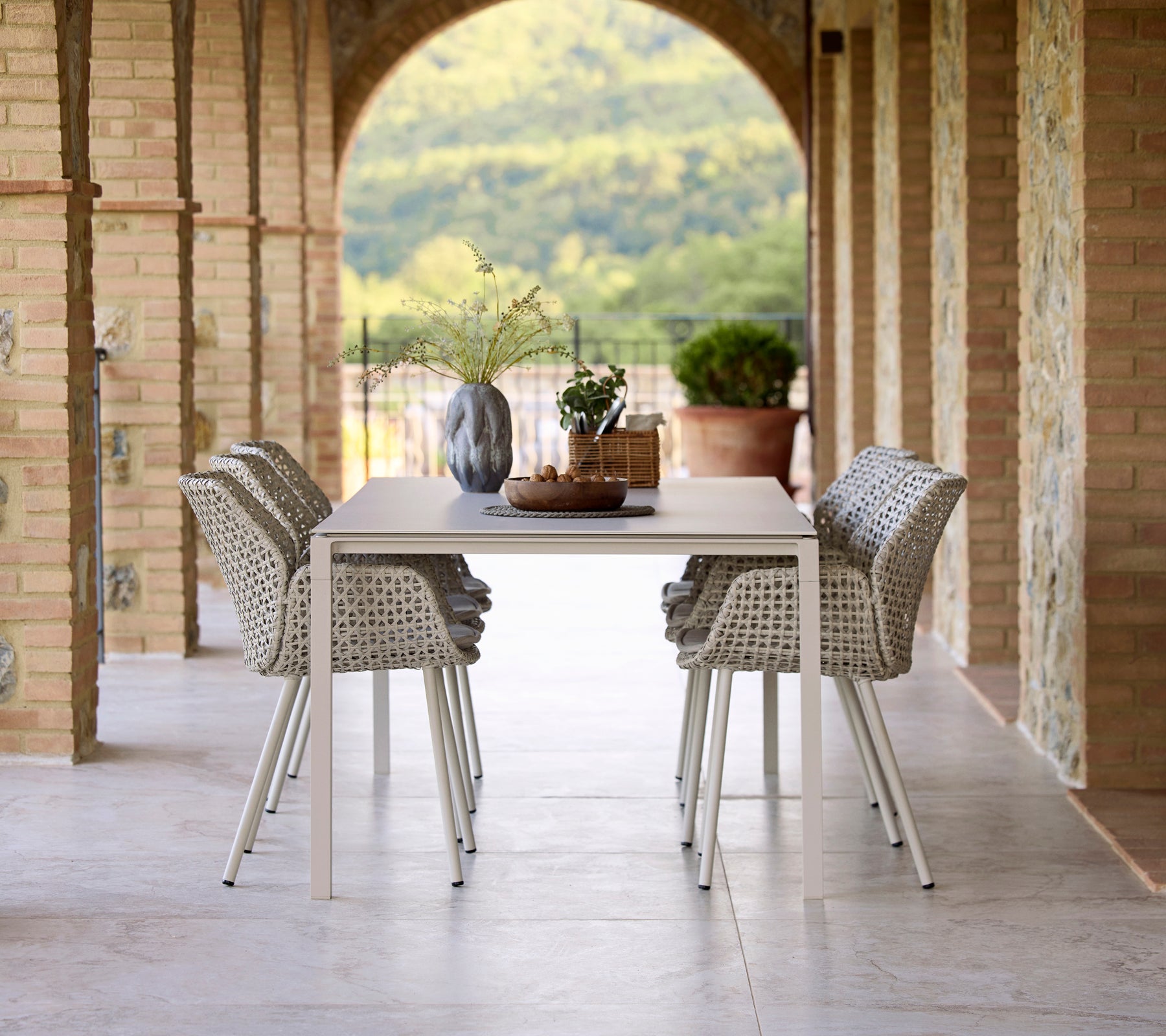 Aménagement de salle à manger élégant avec une table à manger Pure sand entourée de chaises de salle à manger Vibe, accentuée par un vase et des éléments décoratifs.